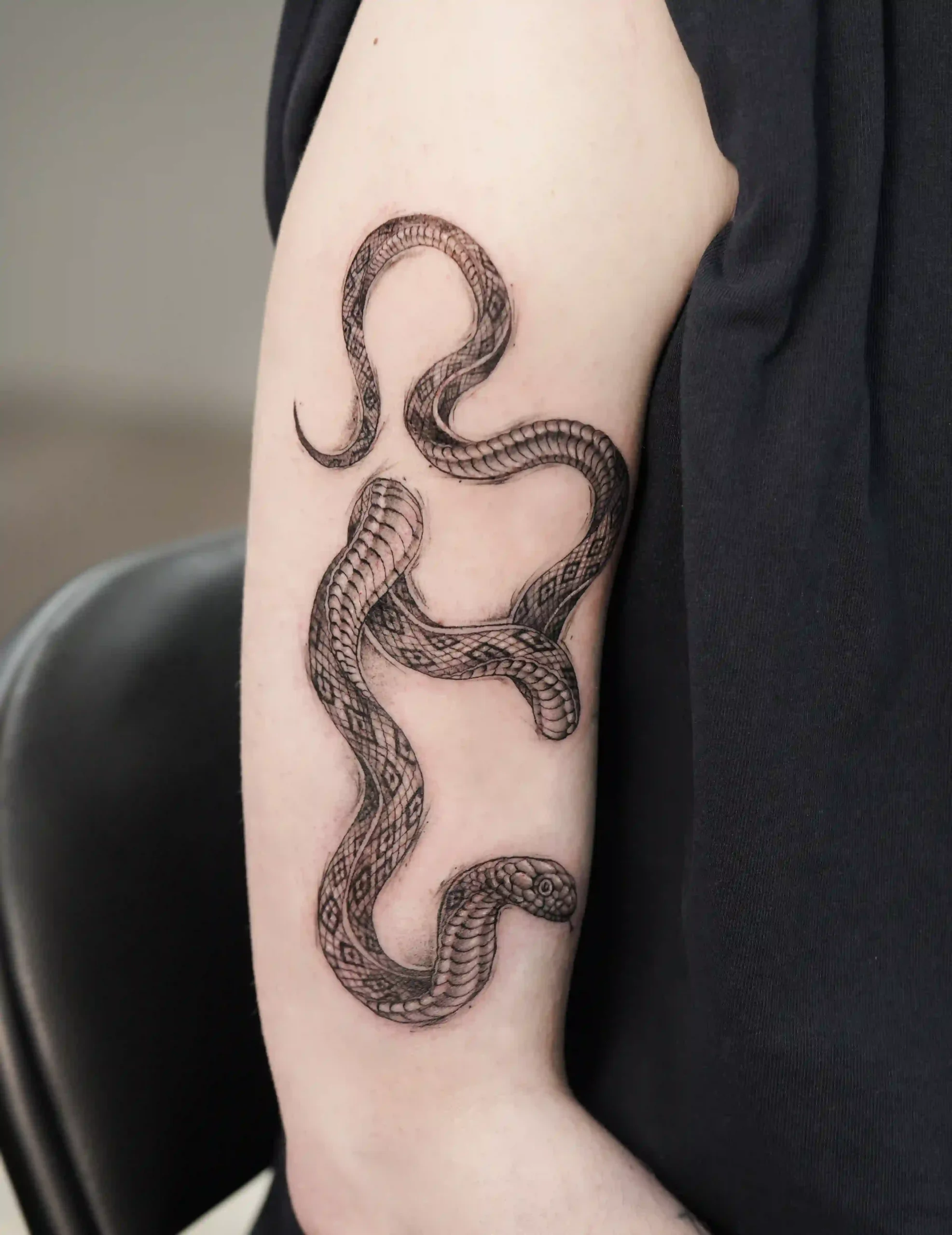 Mikrorealismus Tattoo, detailreiche Schlange in Schwarz-Grau, auf der Rückseite des Oberarms